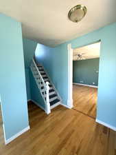 Stairway with wood finished floors, ceiling fan, and a textured ceiling