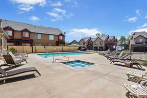 Community pool with a residential view, a hot tub, and a patio