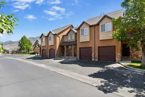 View of property featuring stone siding, stucco siding, a garage, a mountain view, and a residential view