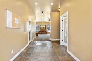 Hallway featuring stone tile floors, french doors, and recessed lighting