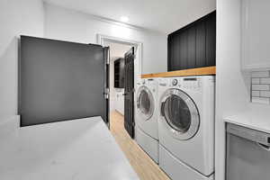 ADU Laundry area with washer and clothes dryer, light wood finished floors, and crown molding