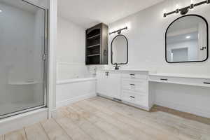 Full bath with a shower stall, wood finished floors, vanity, and a garden tub