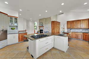 Kitchen with black gas cooktop, decorative backsplash, dark stone countertops, light tile patterned floors, and recessed lighting