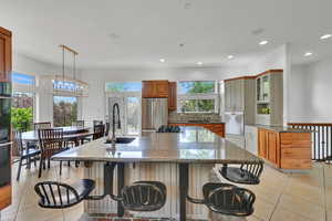 Kitchen featuring freestanding refrigerator, a breakfast bar, recessed lighting, light tile patterned floors, and a large island