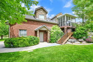 View of side of ADU with a sunroom, a side yard, stairs, brick siding, and stone siding