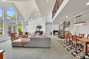 Carpeted living room with stairway, high vaulted ceiling, rail lighting, recessed lighting, and beamed ceiling
