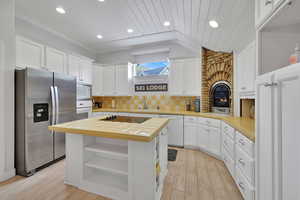 ADU Kitchen with stainless steel  appliances, white cabinetry, open shelves, recessed lighting, and tile countertops, and bricked in fireplace