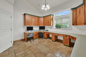 Pantry/Home office with stone tile flooring, built in desk, a chandelier, and high vaulted ceiling