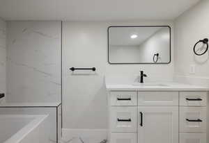 Full bathroom with marble finish flooring, vanity, and a tub to relax in