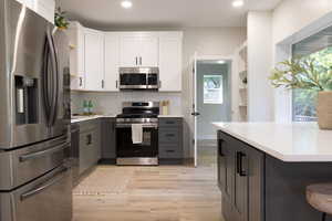 Kitchen featuring appliances with stainless steel finishes, gray cabinetry, light countertops, tasteful backsplash, and recessed lighting