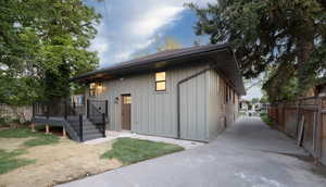 View of front of property with board and batten siding, a wooden deck, and driveway