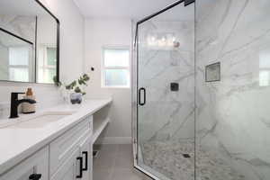 Full bath with vanity, a marble finish shower, and tile patterned flooring