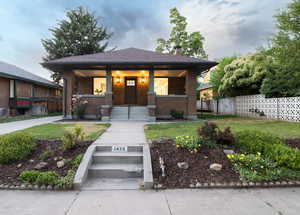 View of front of house with brick siding, a chimney, and a porch