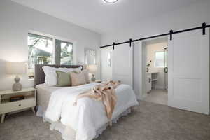 Bedroom with a barn door and light carpet