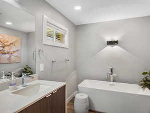 Full bathroom featuring a freestanding bath, wood finished floors, vanity, and recessed lighting