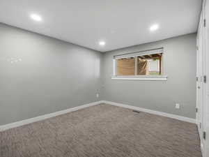 Carpeted empty room featuring recessed lighting