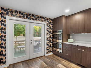 Kitchen with double oven, french doors, light countertops, wood finished floors, and modern cabinets