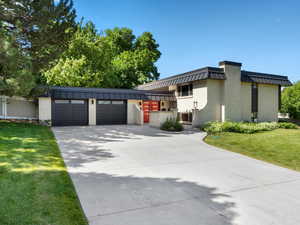 View of front of property with an attached garage, brick siding, concrete driveway, and a front lawn