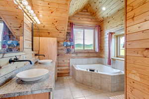Full bathroom with a garden tub, double vanity, vaulted ceiling, wood ceiling, and tile patterned flooring