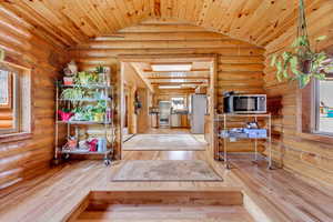 Entryway featuring vaulted ceiling, hardwood / wood-style flooring, wooden ceiling, and rustic walls