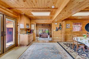 Kitchen with a wood ceiling with exposed beams, light wood-style floors, rustic walls, and healthy amount of natural light