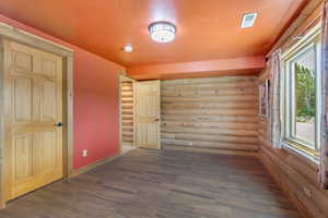 Spare room with log walls, a smoke detector, and dark wood-style flooring