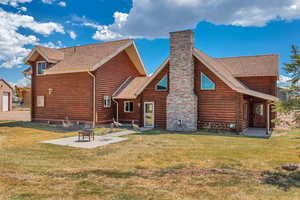 Rear view of house featuring a patio, a shingled roof, a lawn, and a chimney
