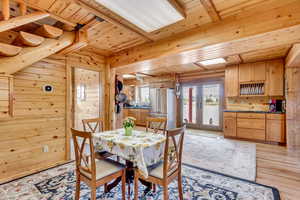 Dining space with wooden ceiling, wood walls, light wood-type flooring, and french doors