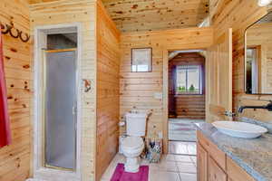 Bathroom with vanity, wood ceiling, a stall shower, wood walls, and tile patterned floors