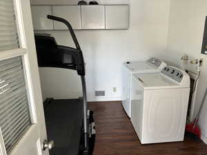 Washroom with washing machine and dryer, wood finished floors, and electric panel