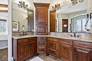 Ensuite bathroom with healthy amount of natural light, double vanity, and a chandelier