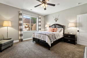 Carpeted bedroom featuring a ceiling fan and baseboards