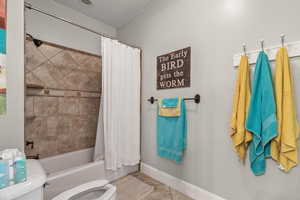 Bathroom featuring shower / bathtub combination with curtain and tile patterned floors