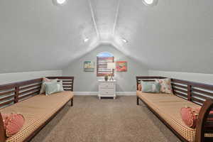 Bedroom featuring a textured ceiling, lofted ceiling, and carpet floors