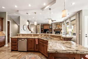 Kitchen with recessed lighting, open floor plan, ceiling fan, a stone fireplace, and light stone countertops