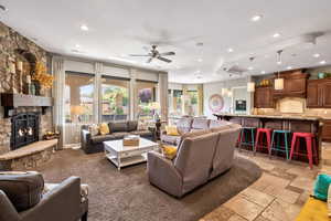 Living area with recessed lighting, ceiling fan, a stone fireplace, and stone tile floors