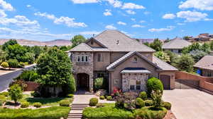 View of front of house with stone siding, stucco siding, concrete driveway, a mountain view, and a gate