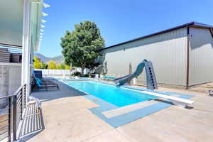 View of swimming pool with a water slide, a diving board, a patio, and a mountain view