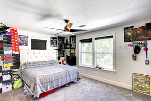 Carpeted bedroom featuring a textured ceiling and ceiling fan
