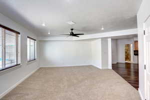 Carpeted empty room featuring ceiling fan and a textured ceiling