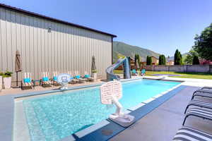 View of swimming pool with a water slide, a mountain view, a fenced backyard, a patio, and a jacuzzi