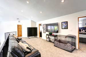 Carpeted living area featuring lofted ceiling and recessed lighting