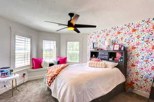 Bedroom featuring carpet flooring, a textured ceiling, ceiling fan, and wallpapered walls