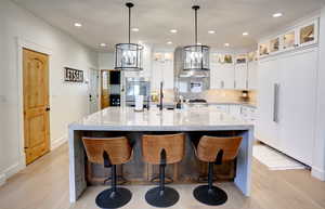 Kitchen featuring paneled refrigerator, light wood finished floors, tasteful backsplash, white cabinets, and recessed lighting
