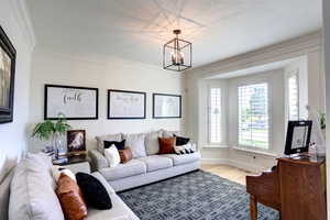 Living area with a chandelier, wood finished floors, crown molding, and a textured ceiling