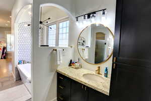 Bathroom with a tub, vanity, a shower, and recessed lighting