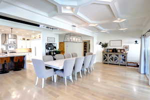 Dining room featuring a chandelier, coffered ceiling, light wood finished floors, and recessed lighting