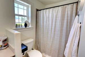 Bathroom featuring toilet and a shower with curtain
