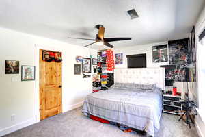 Bedroom with carpet floors, a textured ceiling, and a ceiling fan