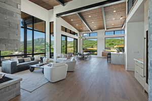 Living area with a wood ceiling with exposed beams, a high ceiling, hardwood / wood-style flooring, and recessed lighting